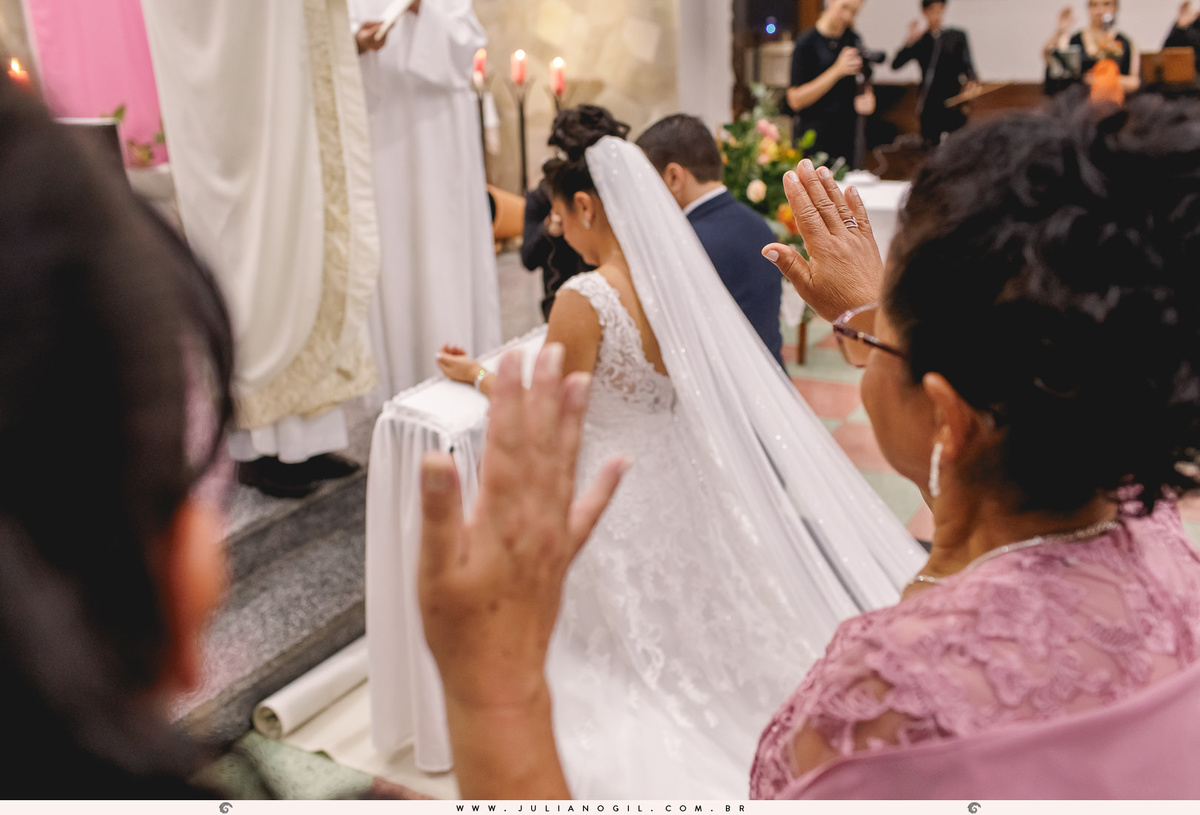 família com as mãos erguidas abençoando o casal que aparece ao fundo da imagem