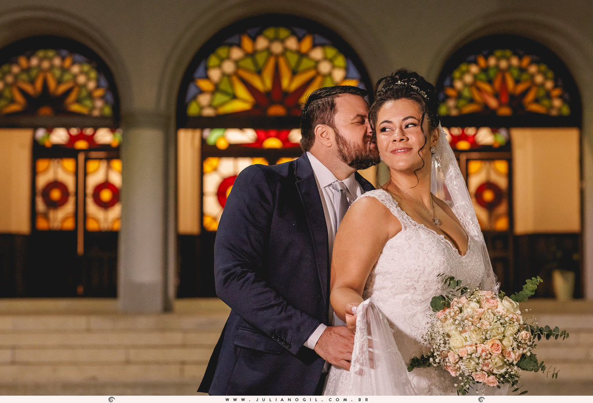 casal em frente a uma igreja com arcos e vitrais coloridos