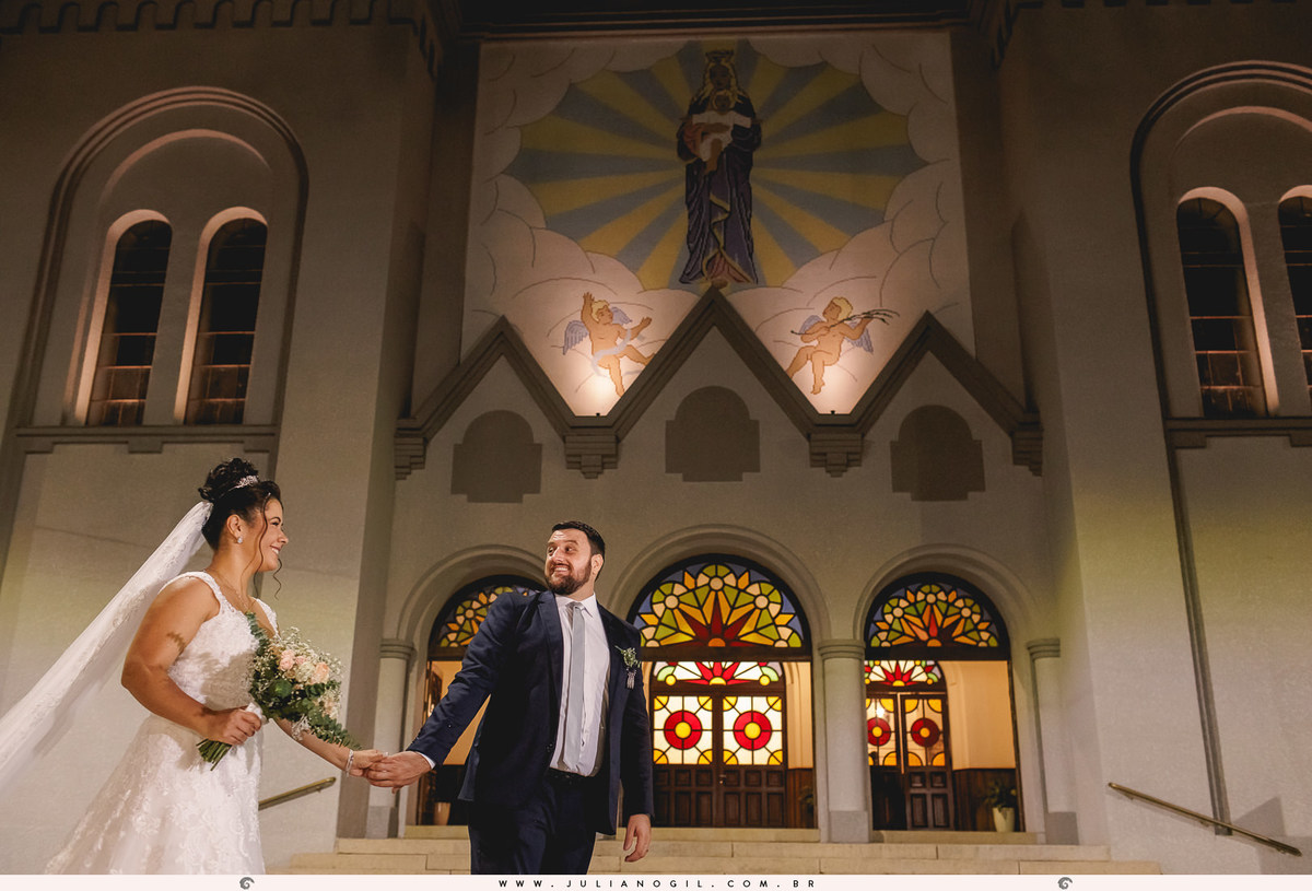casal caminhando em frente a igreja, ao fundo igreja com vitrais coloridos e imagem religiosa