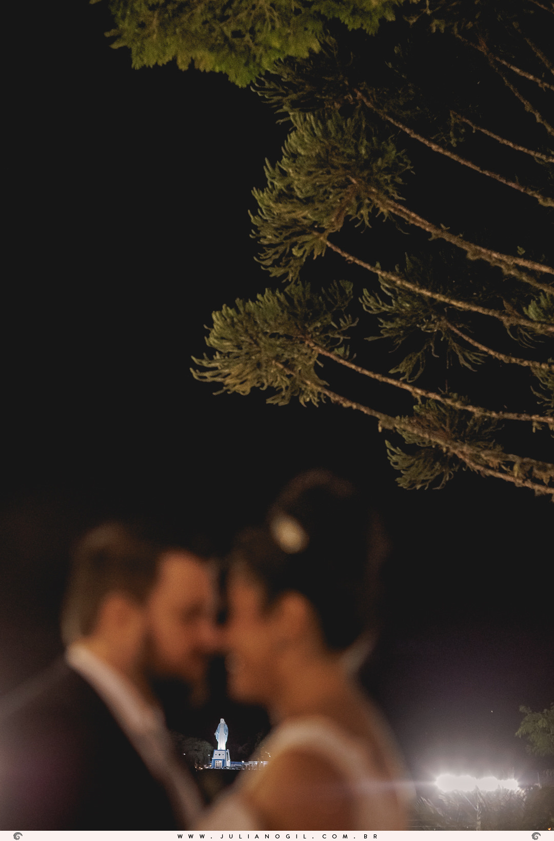 casal desfocado em primeiro plano, ao fundo a imagem de nossa senhora das graças