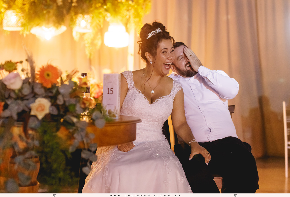 casal sentados próximos a uma mesa na festa de casamento gargalhando