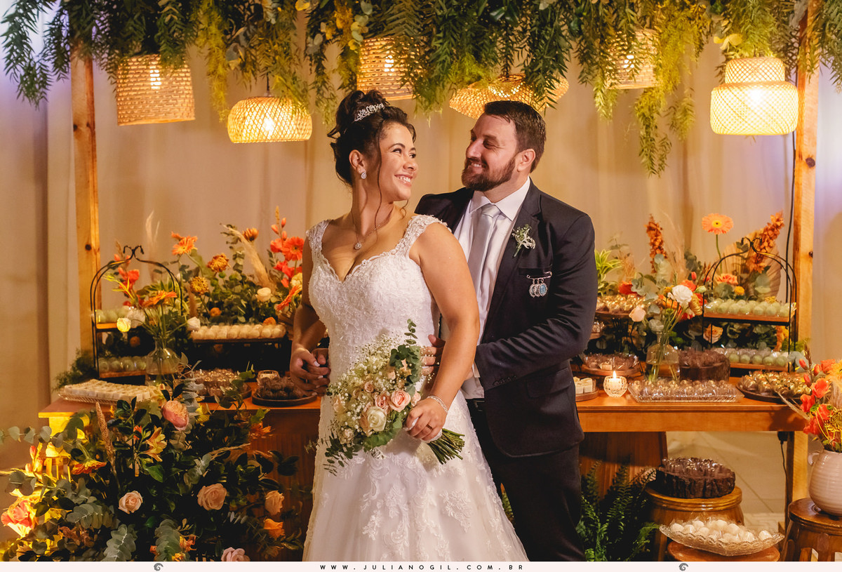 casal em frente a mesa de doces na festa de casamento