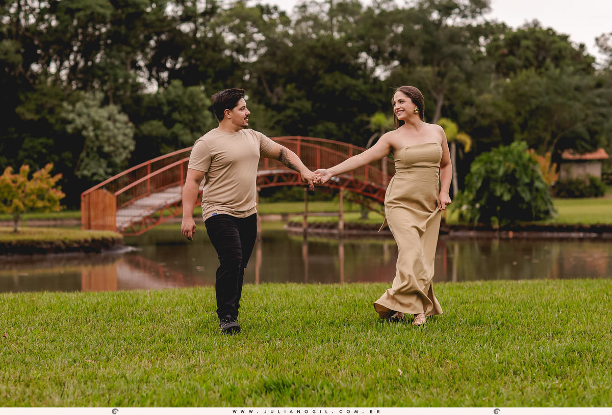 casal caminhando em um gramado com uma ponte ao fundo
