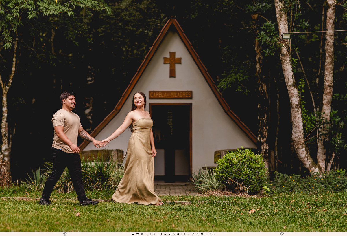 casal caminhando em frente a uma capela dentro da floresta