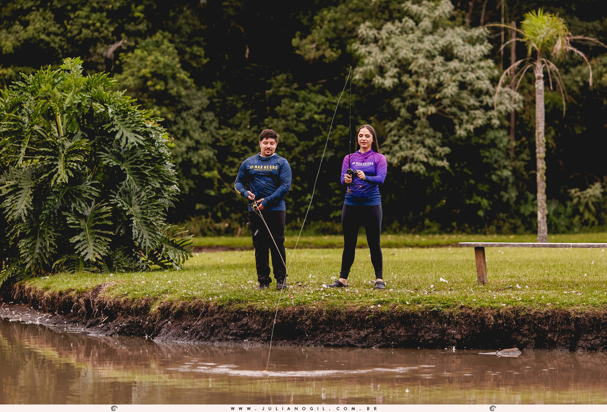 casal pescando a beira de um tanque