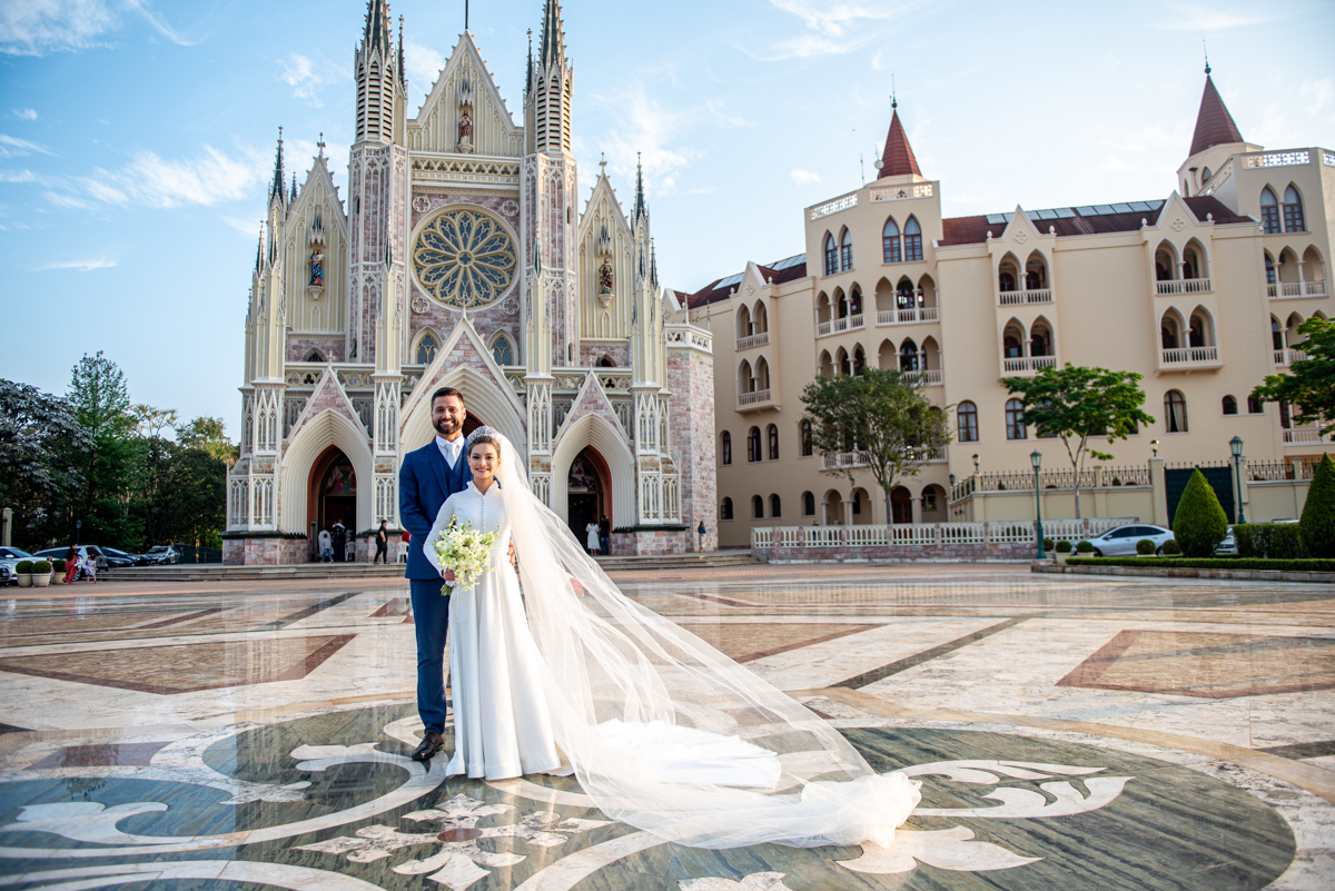 Linda foto com a igreja de fundo aos noivos.