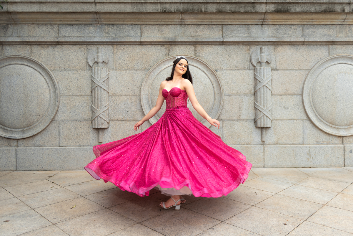 Sob os detalhes dourados do Museu, a debutante irradia sofisticação em seu vestido de gala impecável.