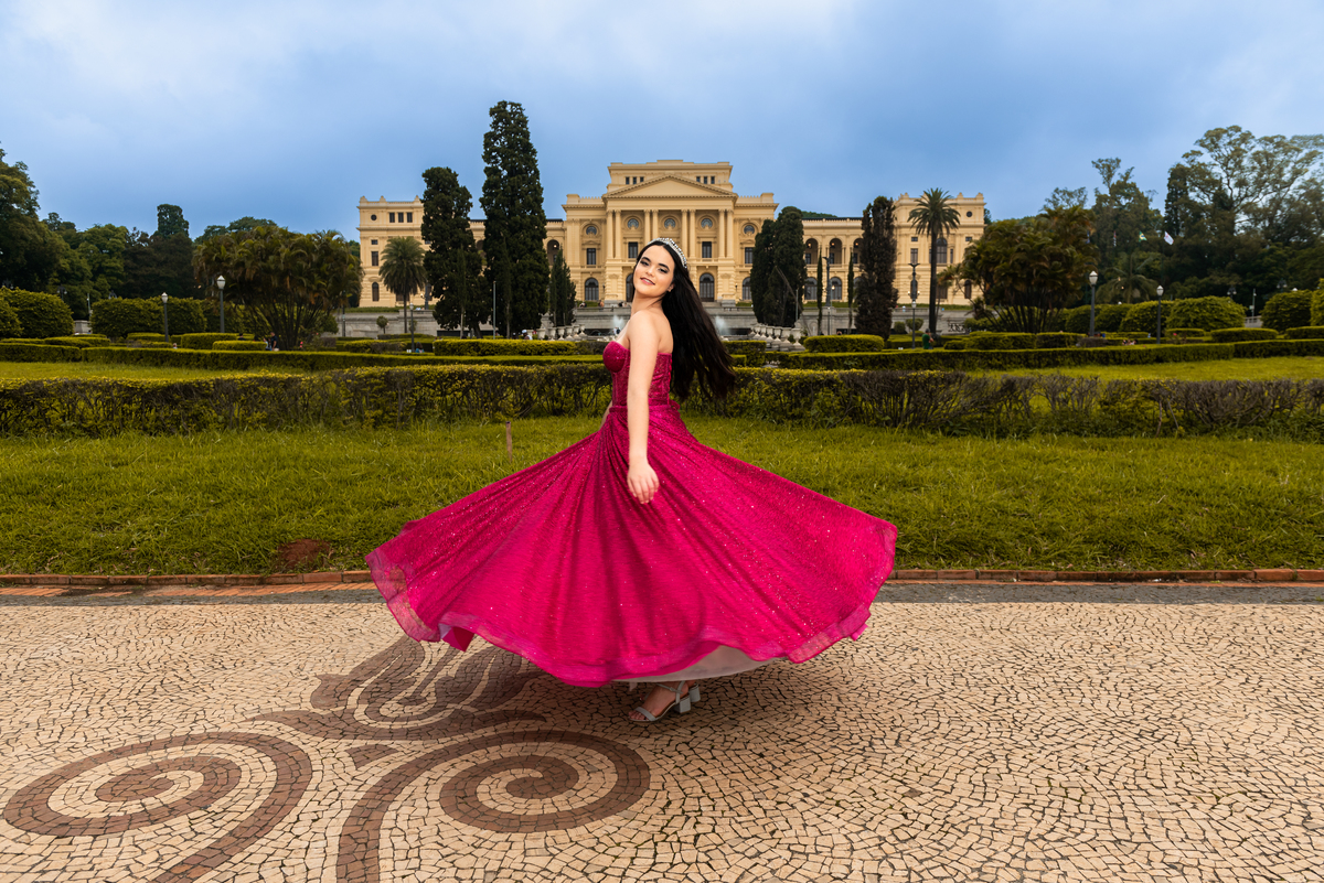 A textura e o brilho do vestido de gala são realçados pelo pôr do sol, capturando a essência do aniversário no Museu.