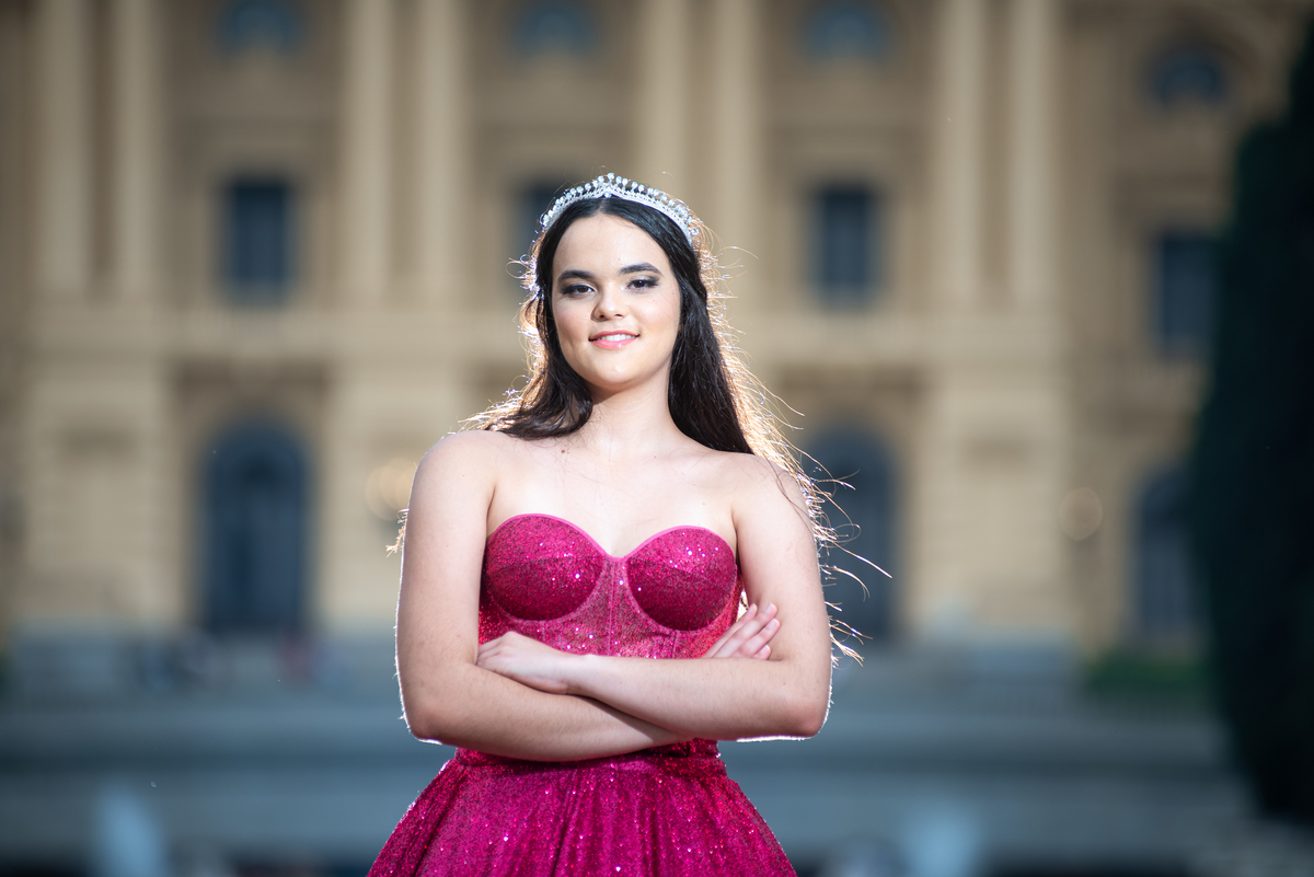 O vestido dourado da debutante se harmoniza perfeitamente com os detalhes clássicos do Museu, criando fotos de cinema.