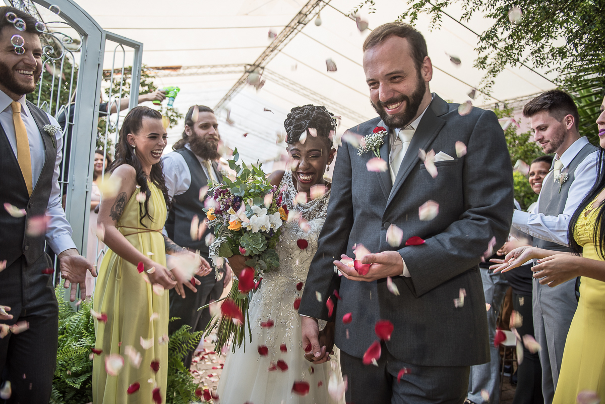 saída dos noivos inter-raciais do altar com chuva de pétalas de flores