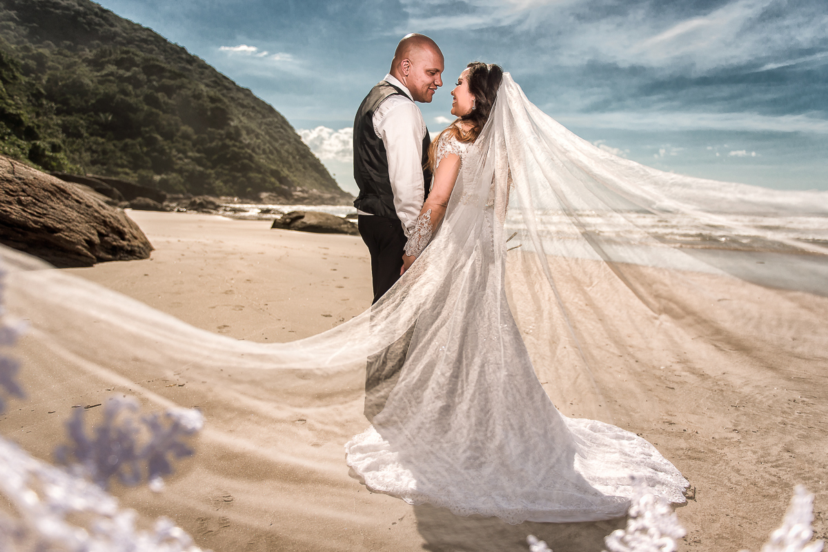 Véu da noiva grande e belo todo aberto para ver a noiva na praia.