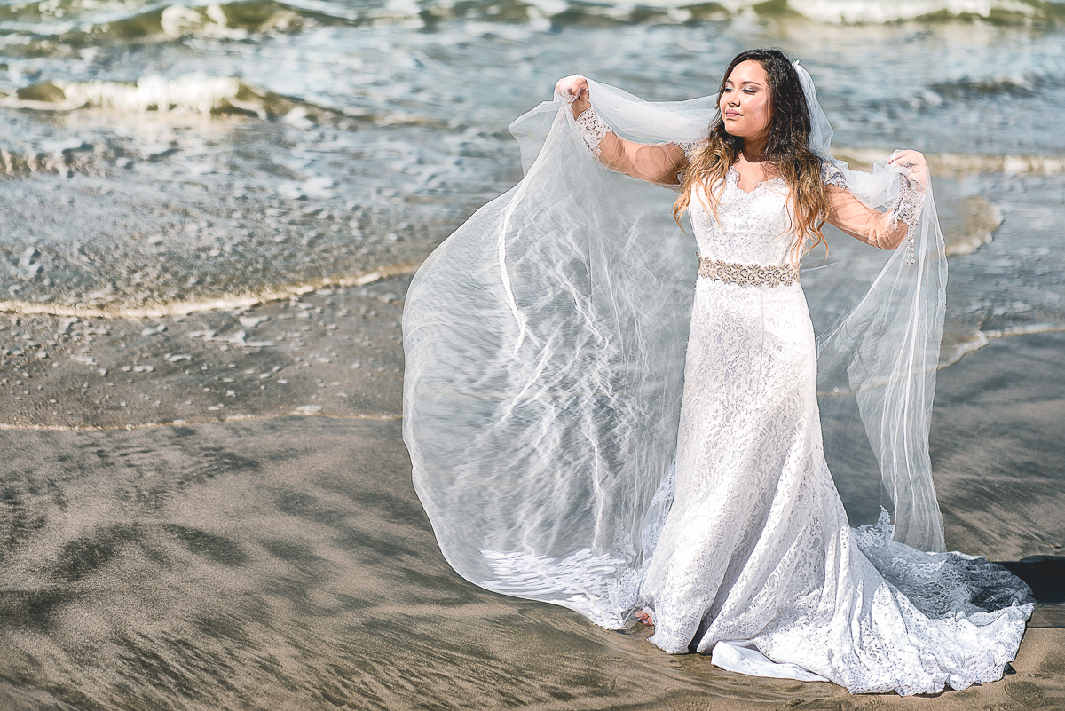 Noiva ao vento com seu véu voando sobre as águas do mar para foto de Alberto Martinez.