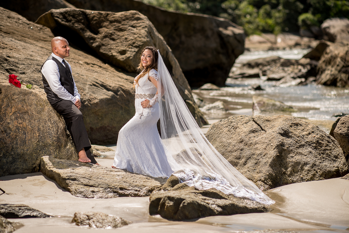 Casal pousando para ensaio fotográfico no canto da praia.