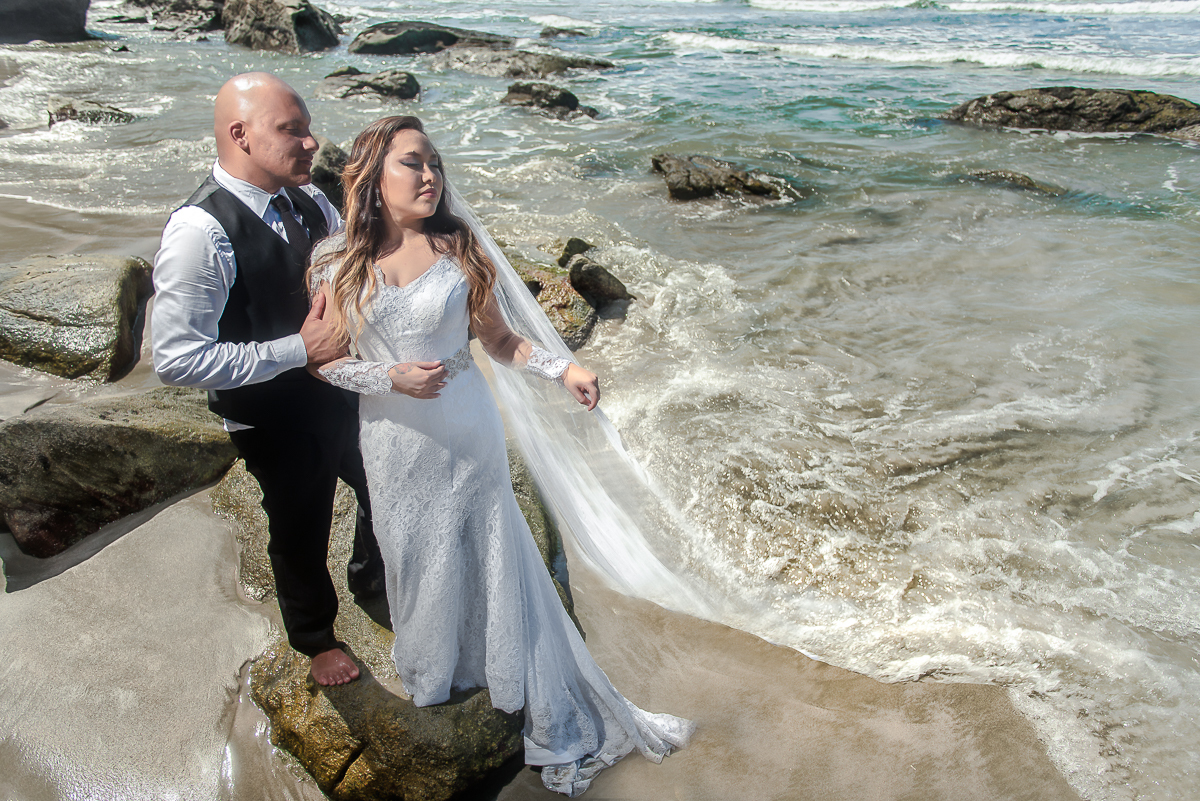 Véu da noiva se mistura com água do mar causando um efeito lindo na foto.