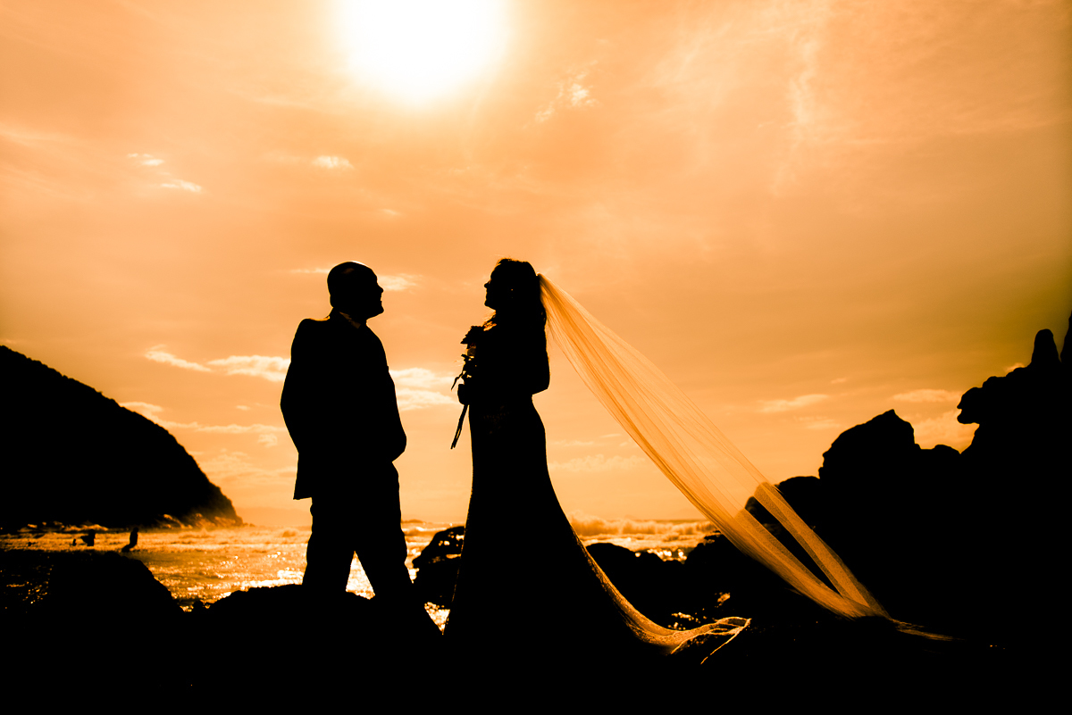 Casal em por do sol com o céu amarelo.