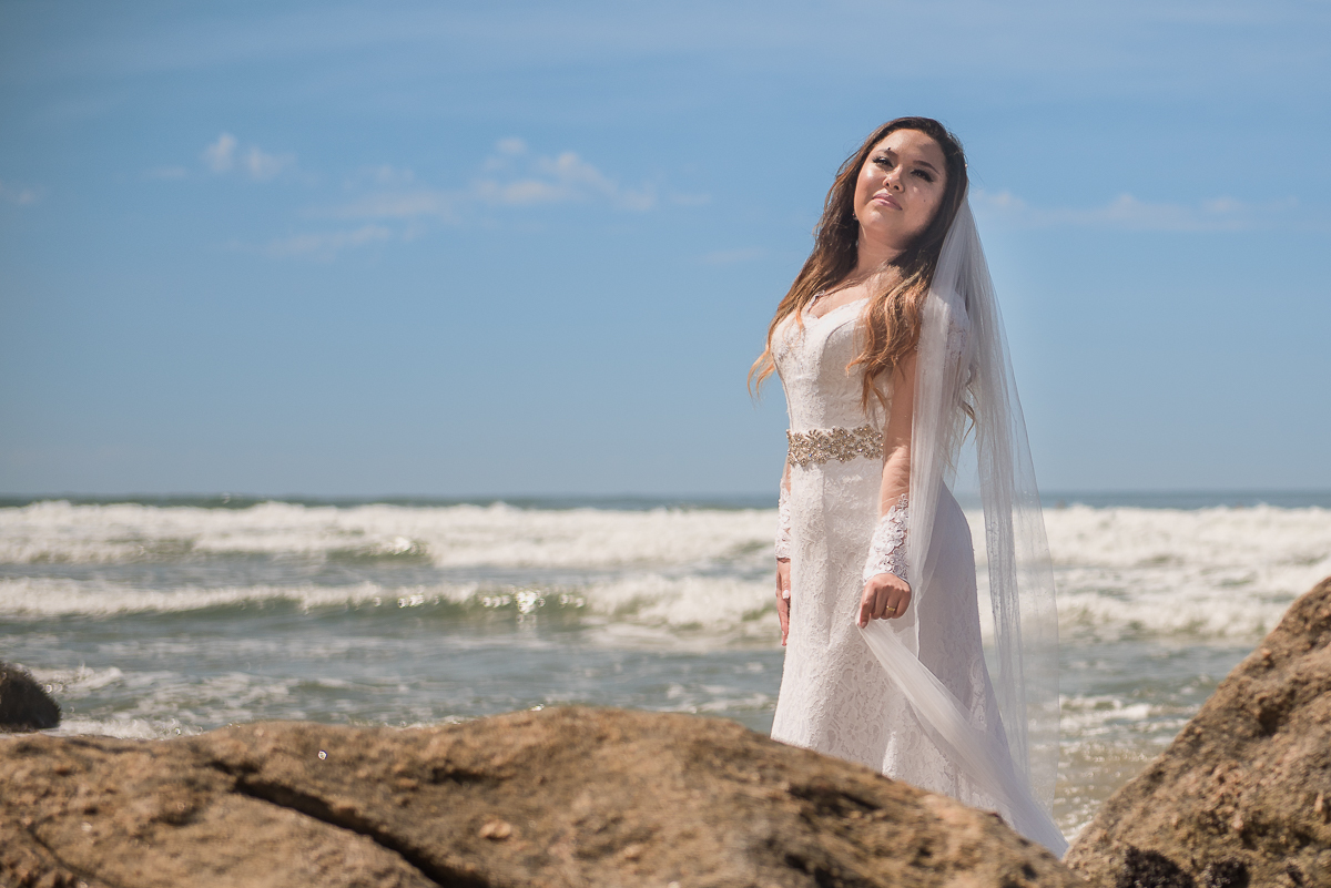 Noiva no céu limpo e mar ao fundo.