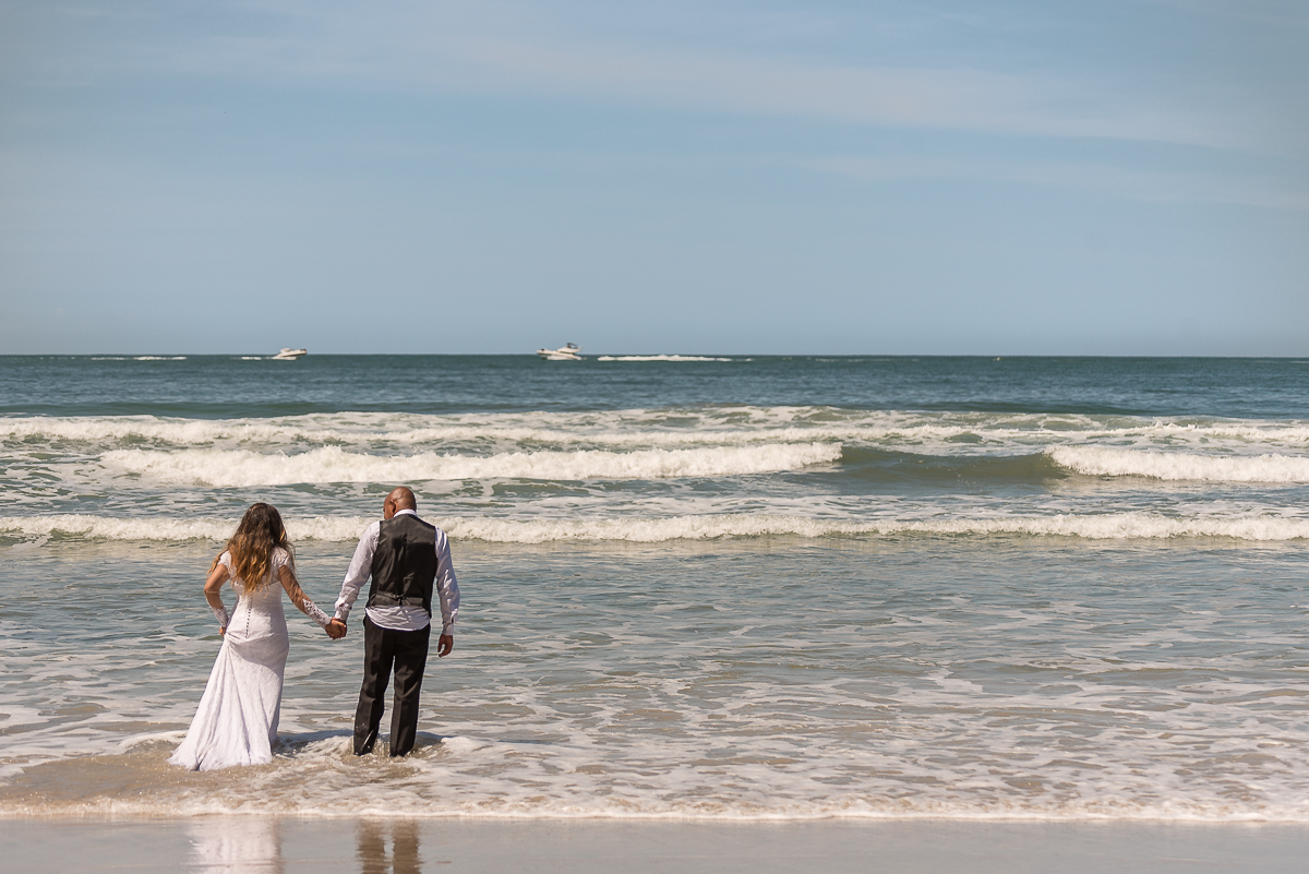 Noivos entram no belo mar limpo do Guarujá.