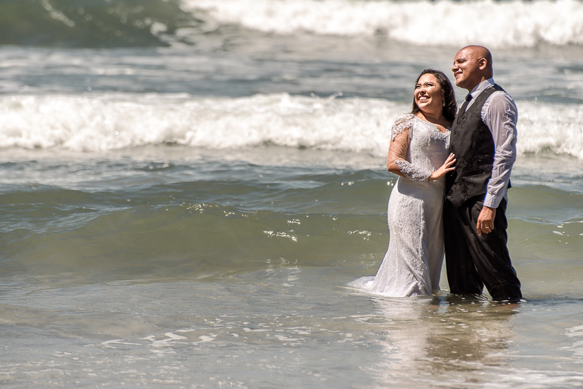 Nas ondas de um mar limpo e belo com o casal se banhando no mar, noivos com ensaio lindo trash the dress.