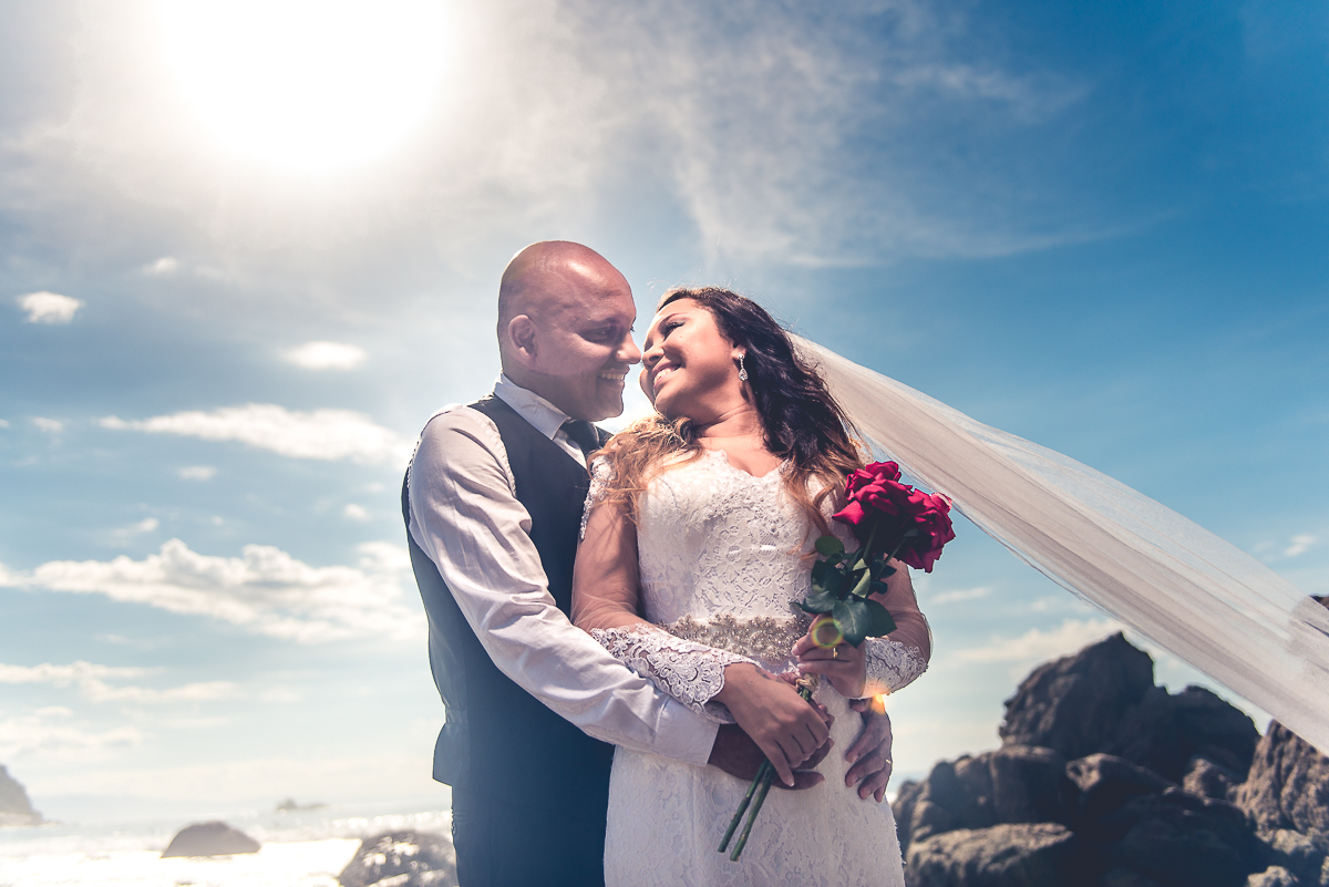 Noivos abraçados sobre um lindo céu da praia.