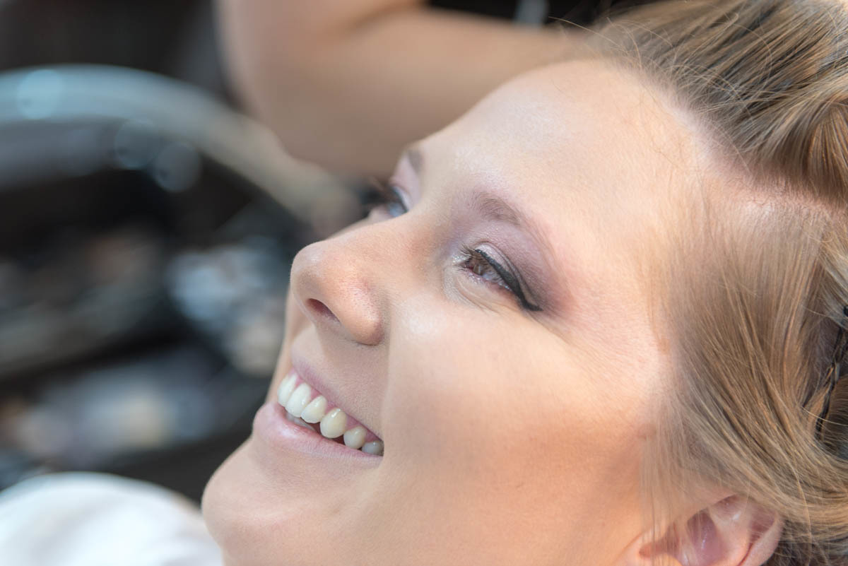 Noiva sorrindo e feliz por estar se arrumando para o grande momento que é seu casamento.