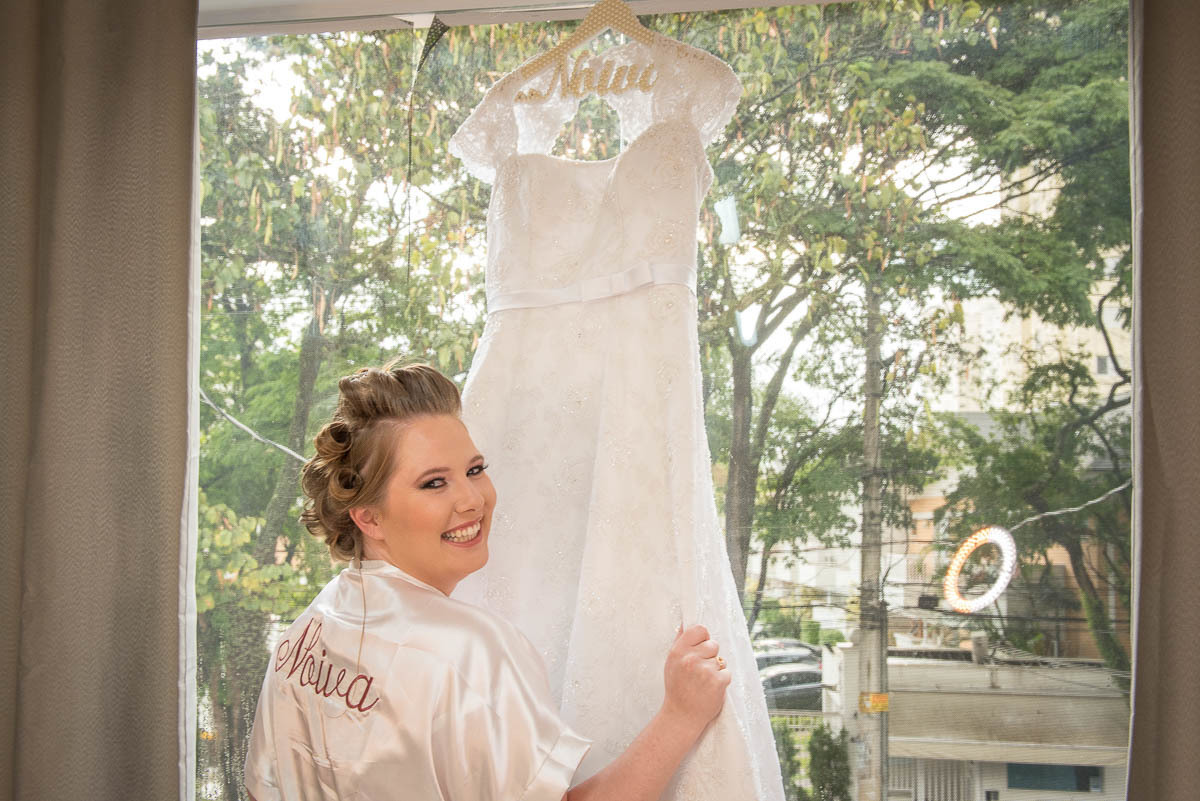 Noiva realizada vendo com seu vestido de noiva que irá colocar em instantes.