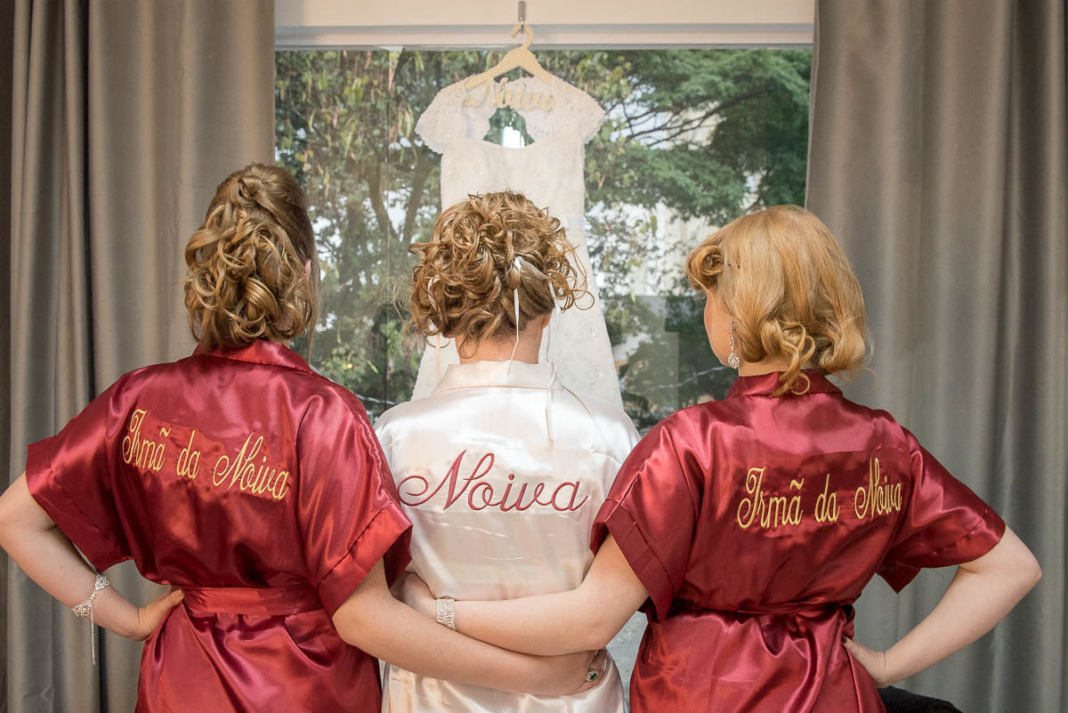 Noivas e suas irmãs admirando o vestido da noiva.