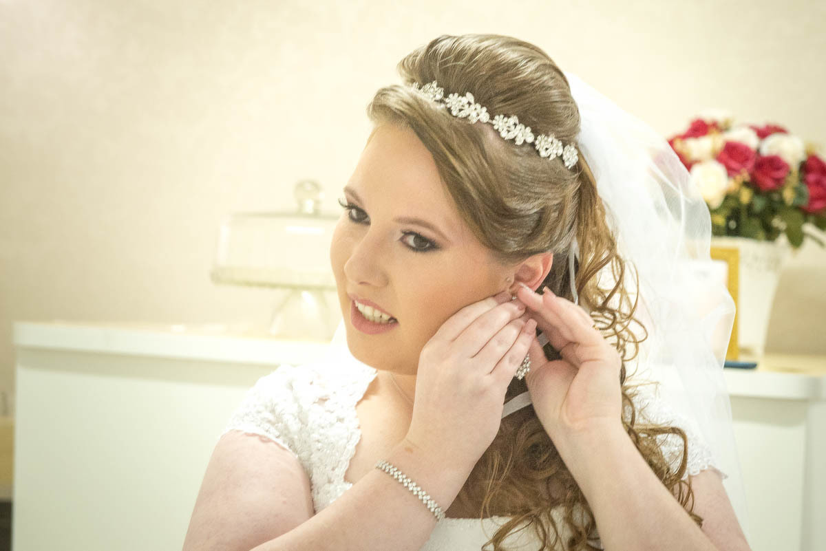 Noiva colocando o brinco para ficar linda.