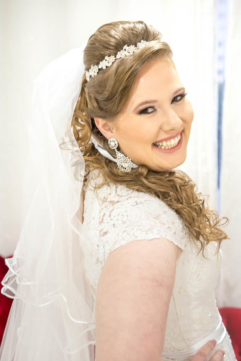 Noiva sorrindo e feliz com o casamento que irá começar em poucos momentos.