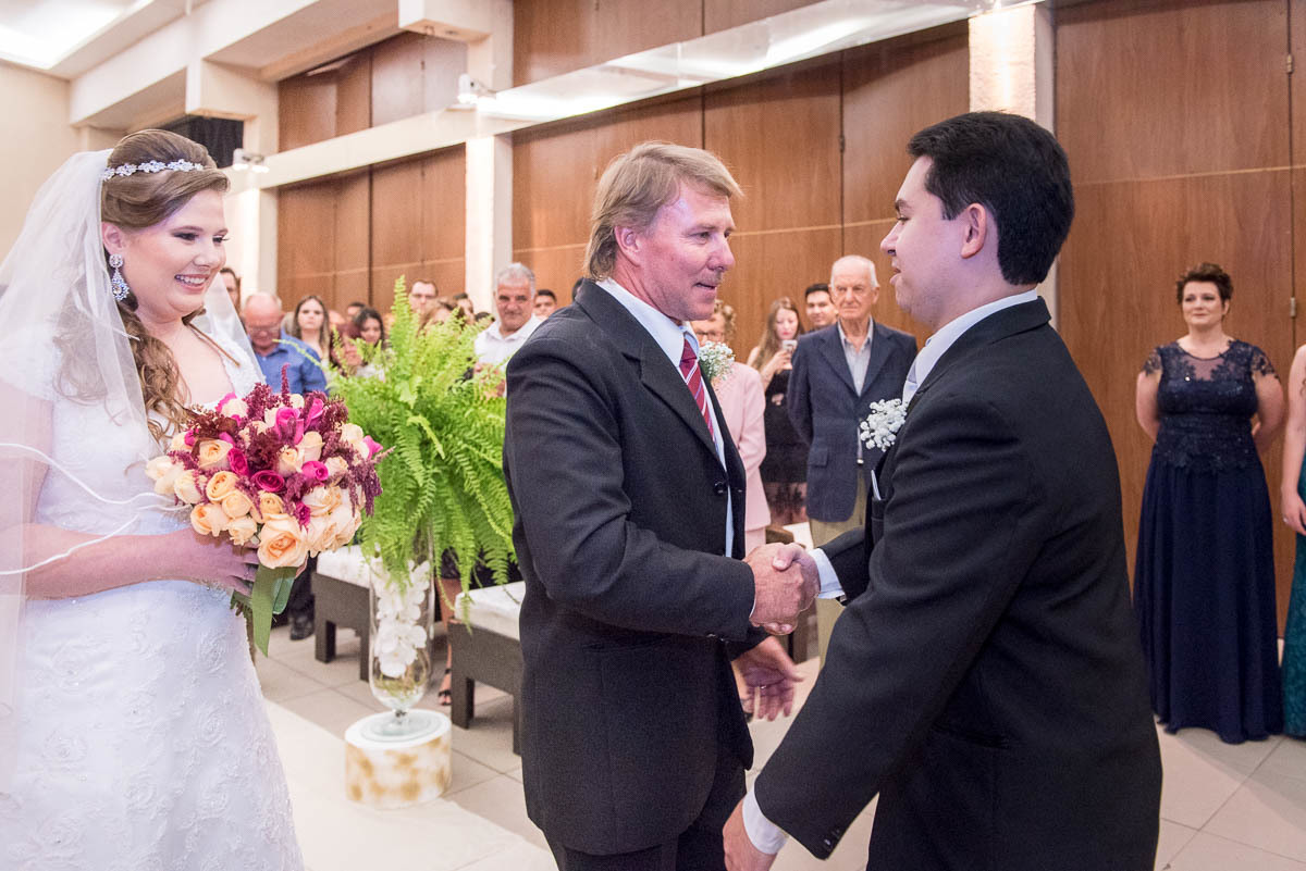 Pai do noiva cumprimenta o noivo no altar.