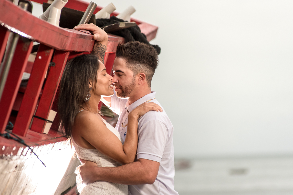 Casal encostado no barco de pesca na praia de Perequê