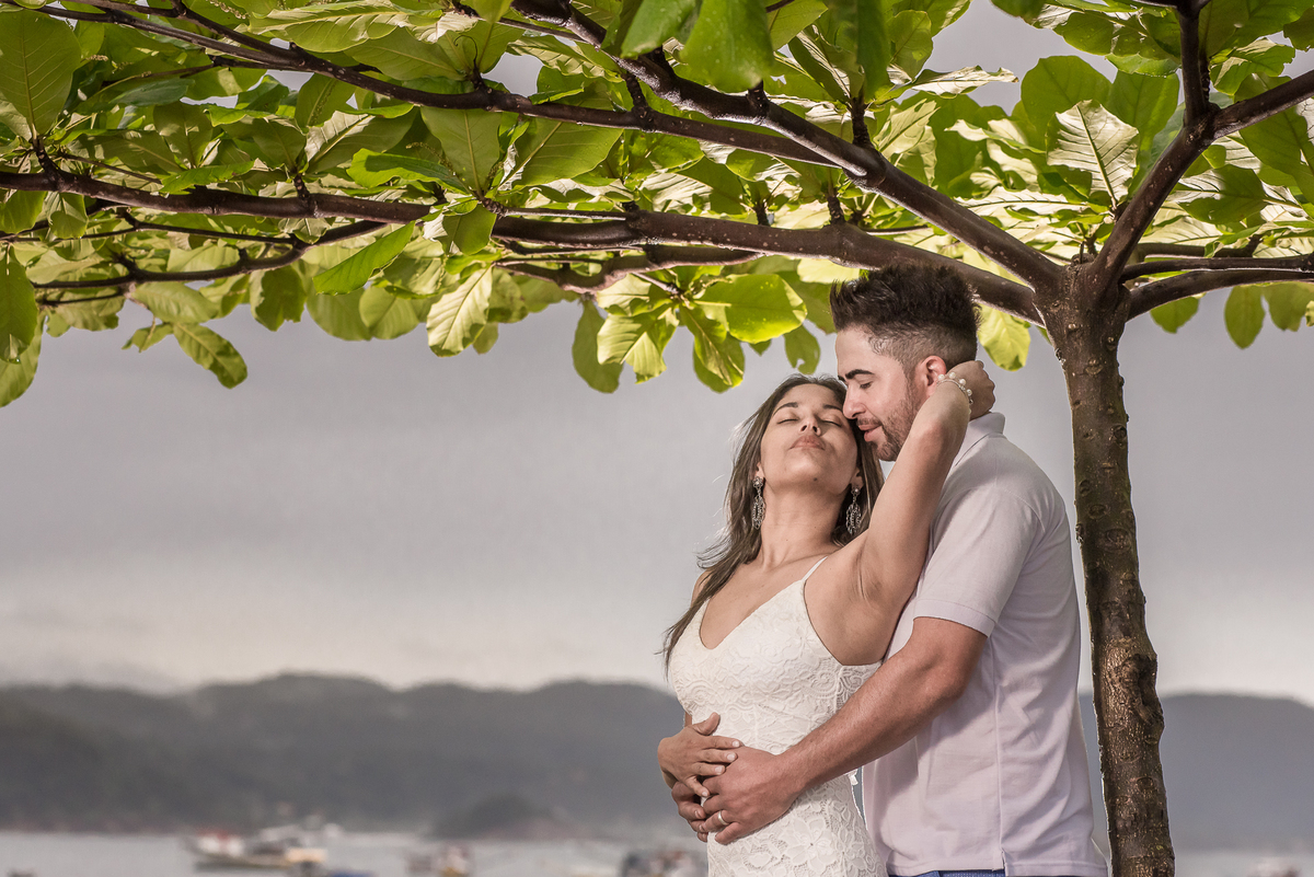 Casal namorando em baixo da arvore na praia, sessão fotográfica