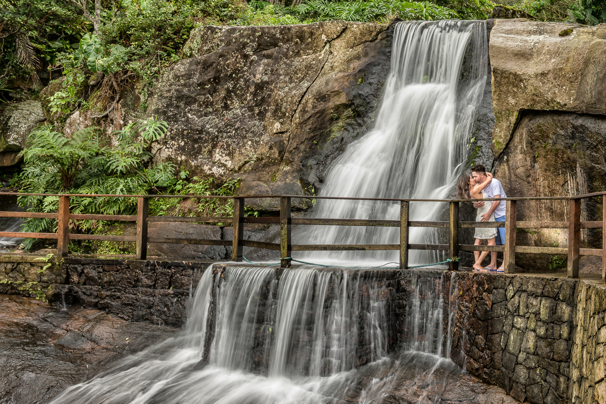 fotografia tirada em baixa velocidade de obturador para formar da cachoeira um véu de noiva com o casal se beijando perto dela