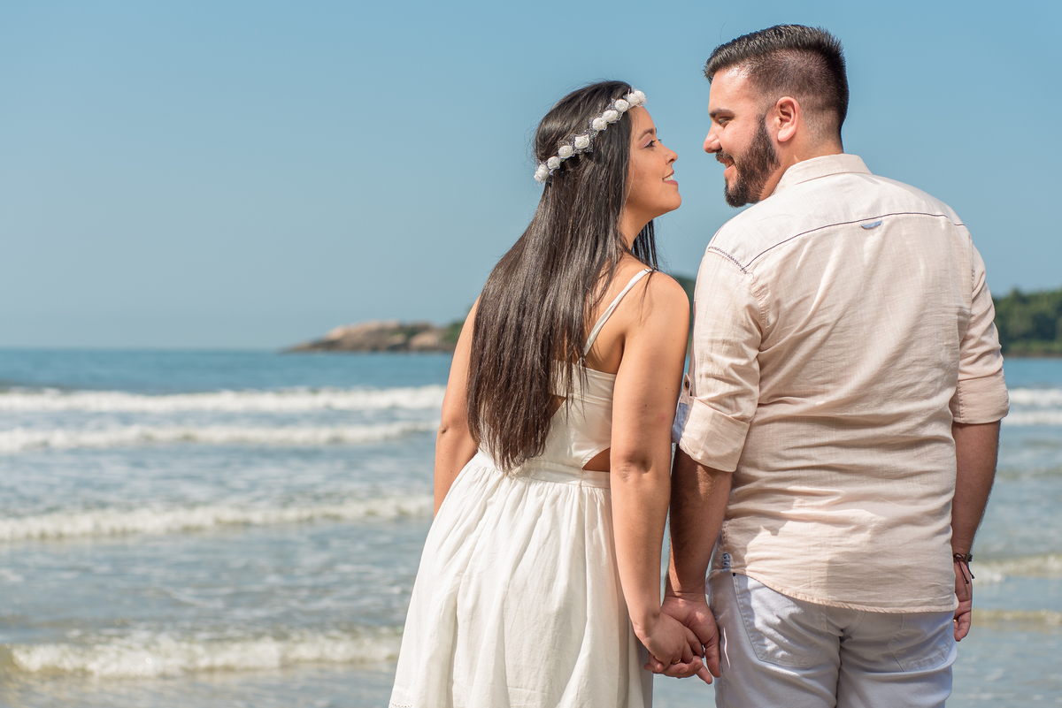 Mar e céu azul na praia com o casal fazendo belíssimas fotografia para seu ensaio de pre casamento.