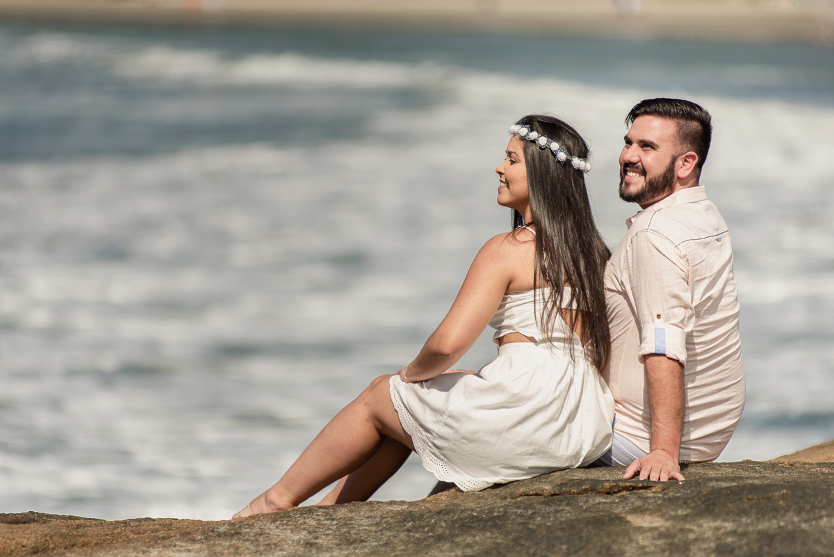Sentados a beira do mar em fotografia feita em momento especial para o casal.