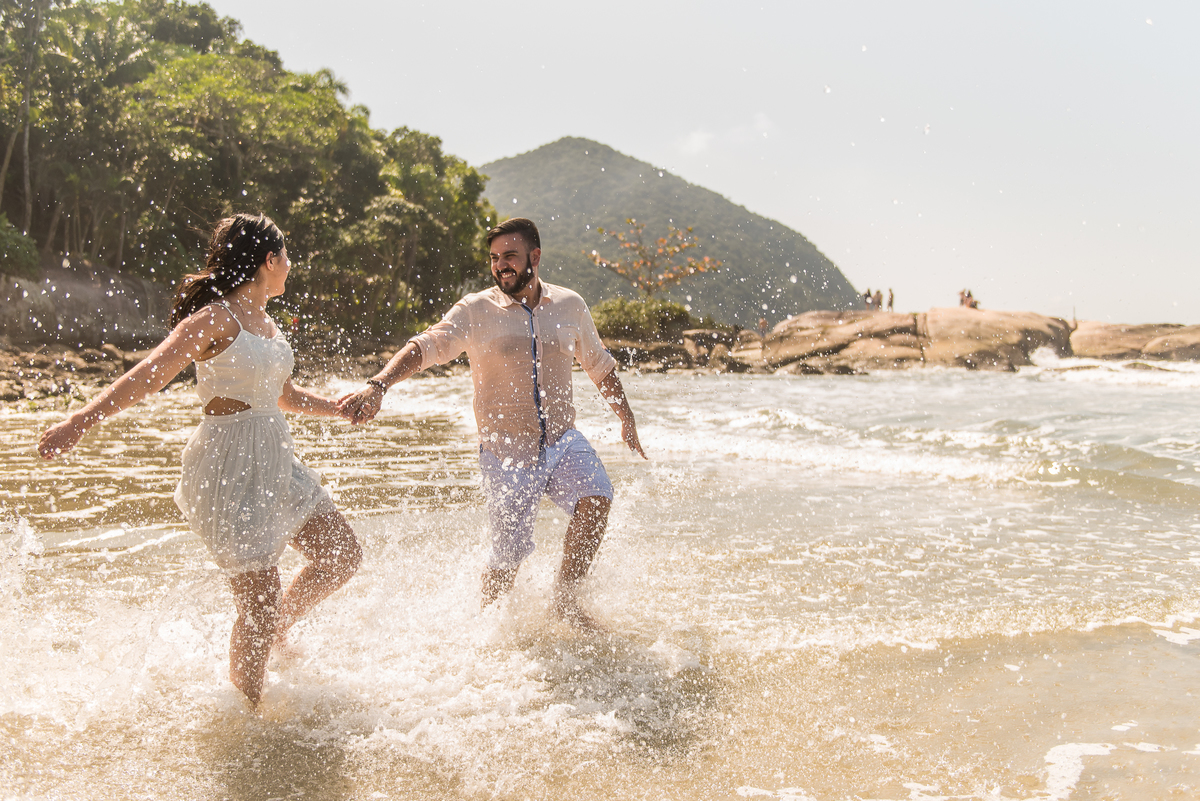 Casal corre dentro d'água felizes em um ensaio que ficará para sempre em suas vidas.