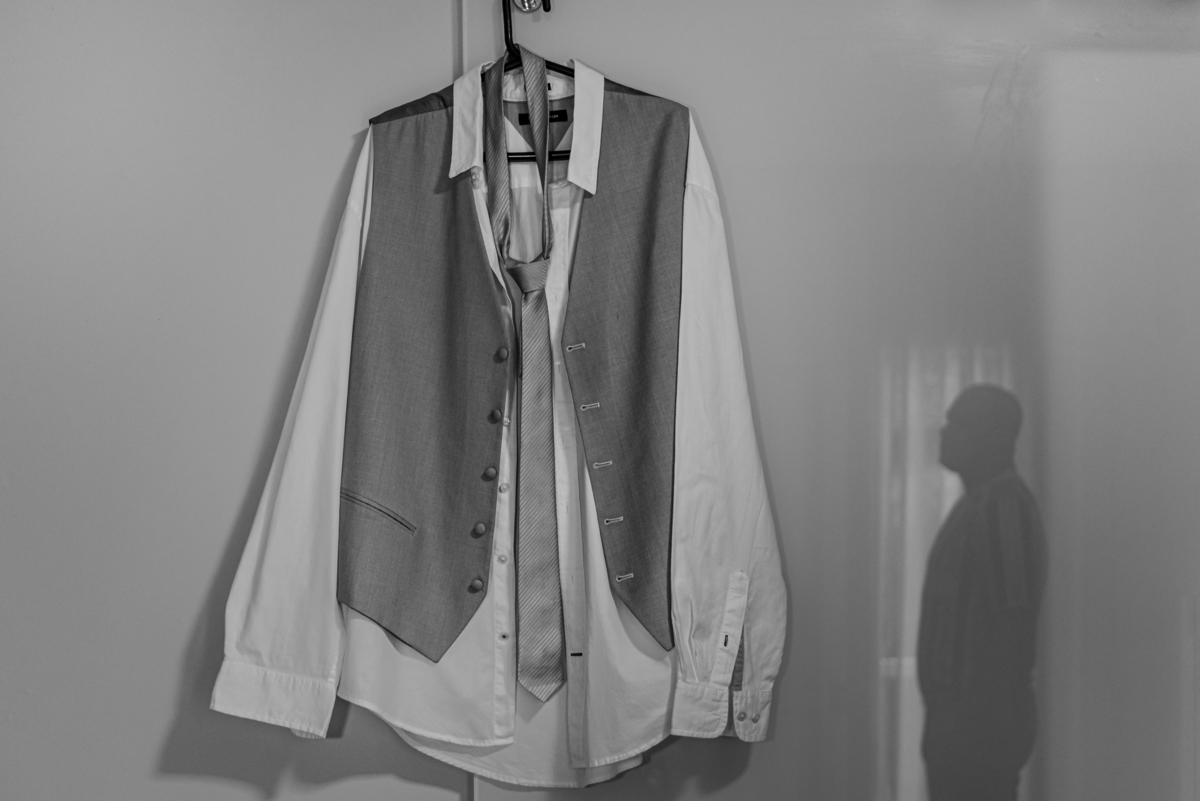 Fotografia do terno e sobra do noivo esperando para colocar a roupa de casamento.