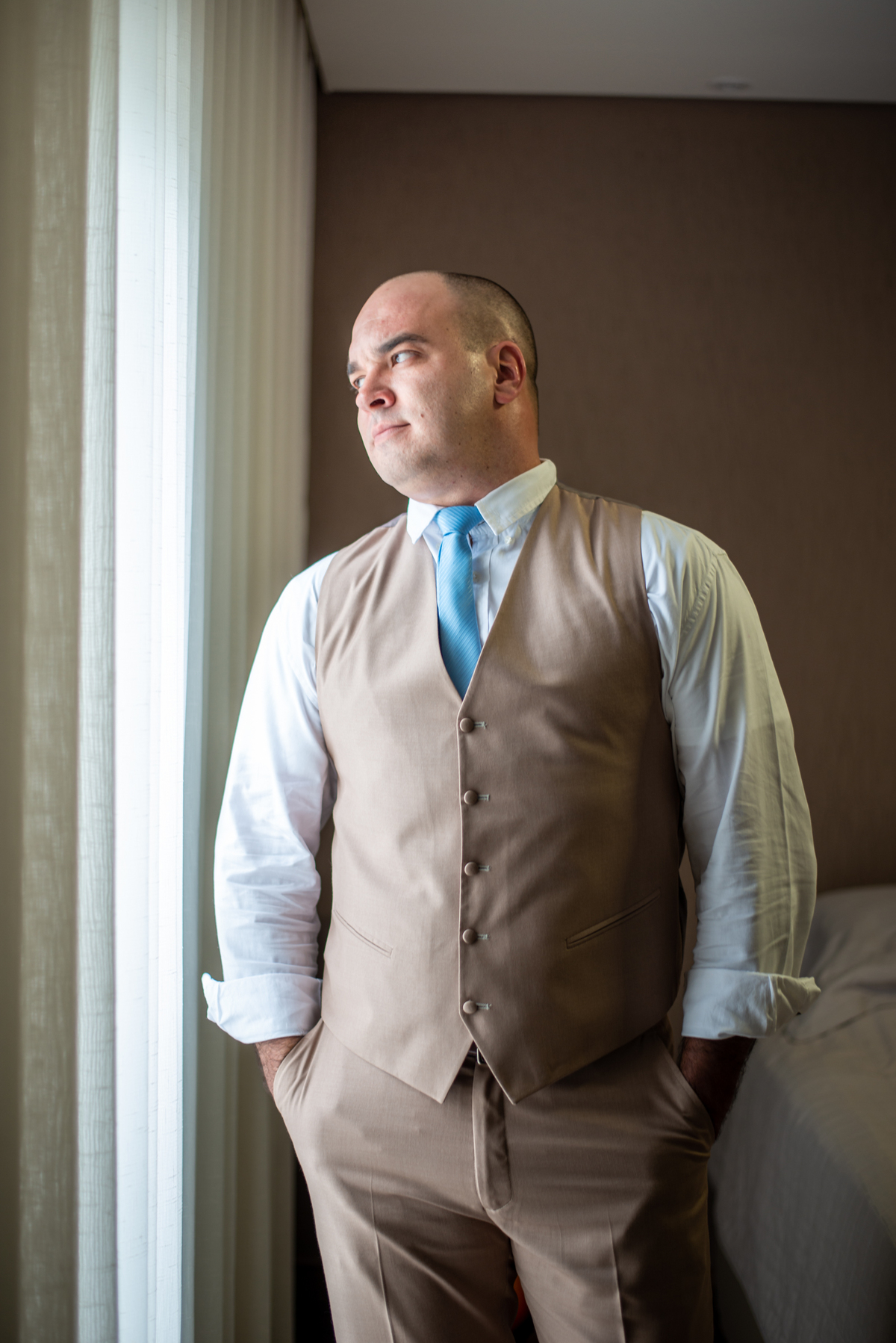 Noivo em frente a janela olhando o que acontece lá fora antes do casamento.