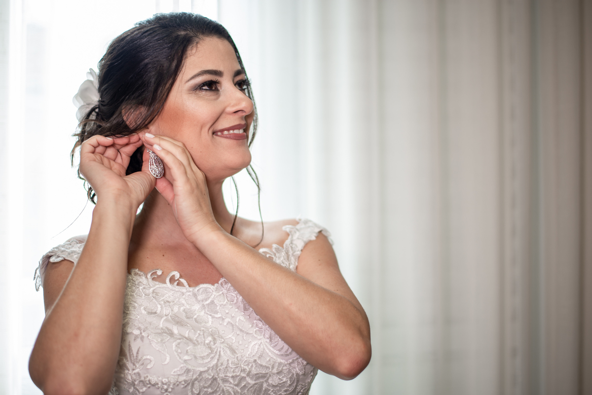 Noiva colocando o brinco para ir se casar.
