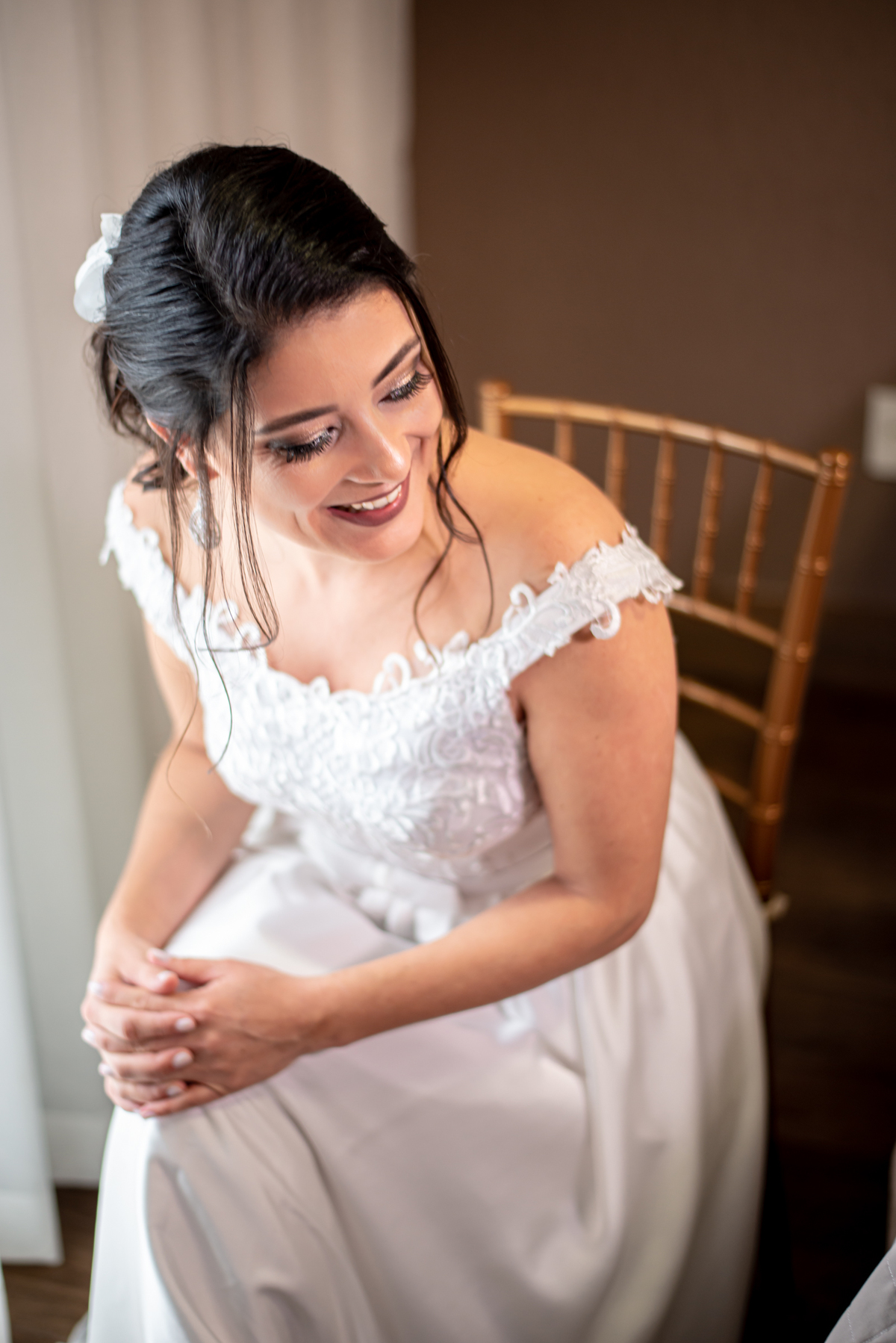 Noiva sentada na cadeira dando um lindo sorriso no dia de seu casamento.