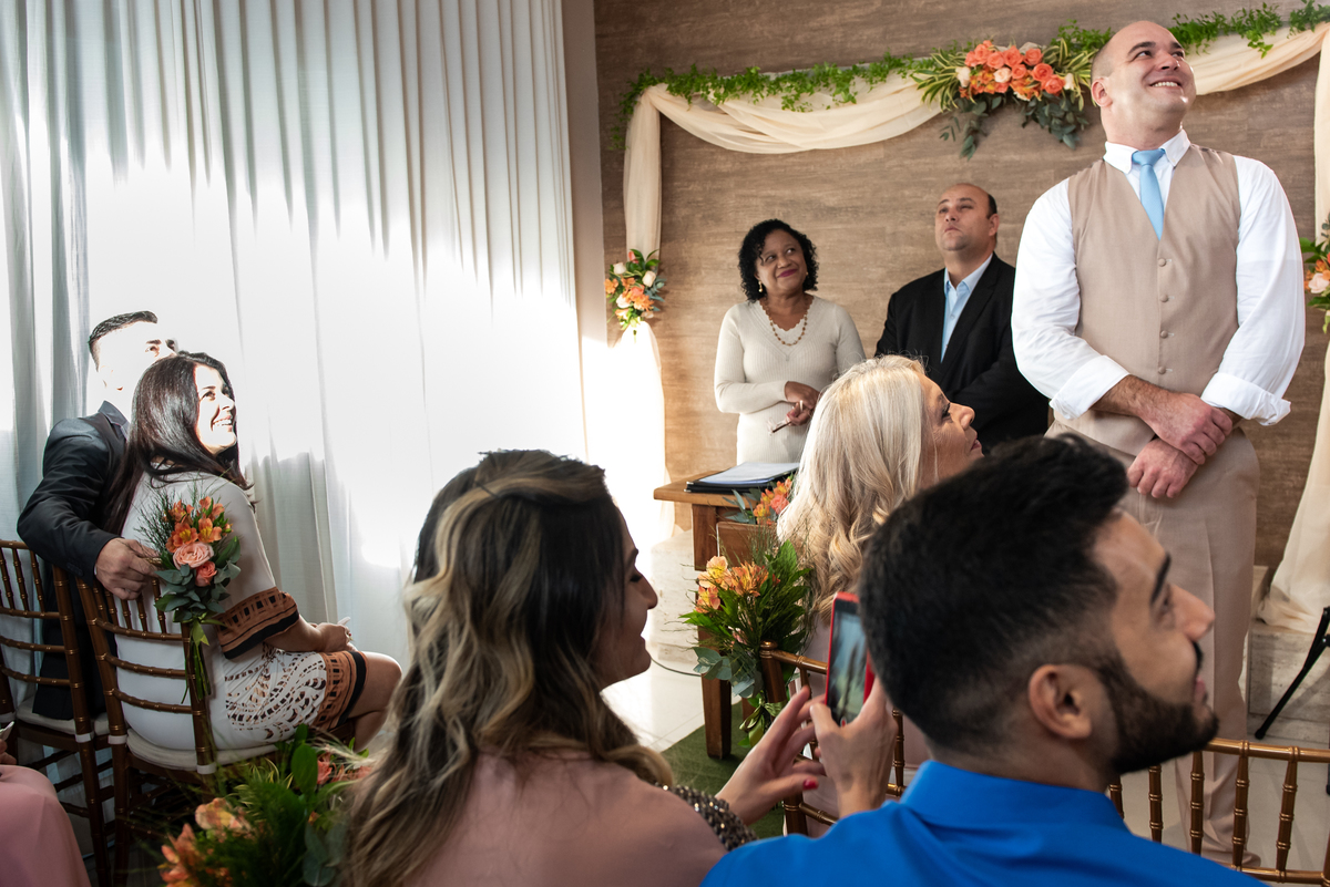 Noivo olhando quando a noiva chega e desce a escada da sala.