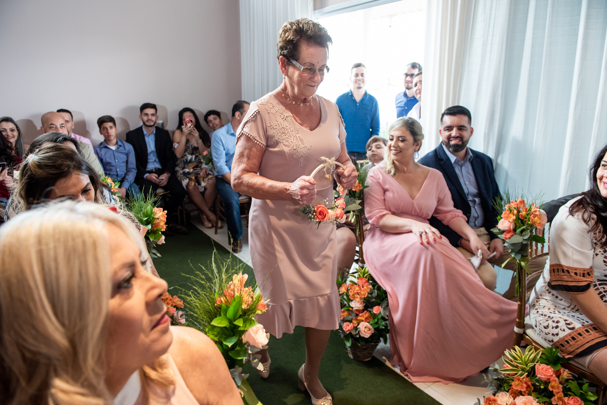 Mãe do noivo traz as alianças para os noivos.