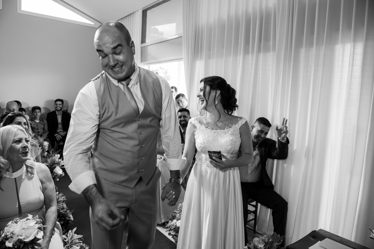 Noivo ri ao se casar na sala de sua casa em casamento civil.