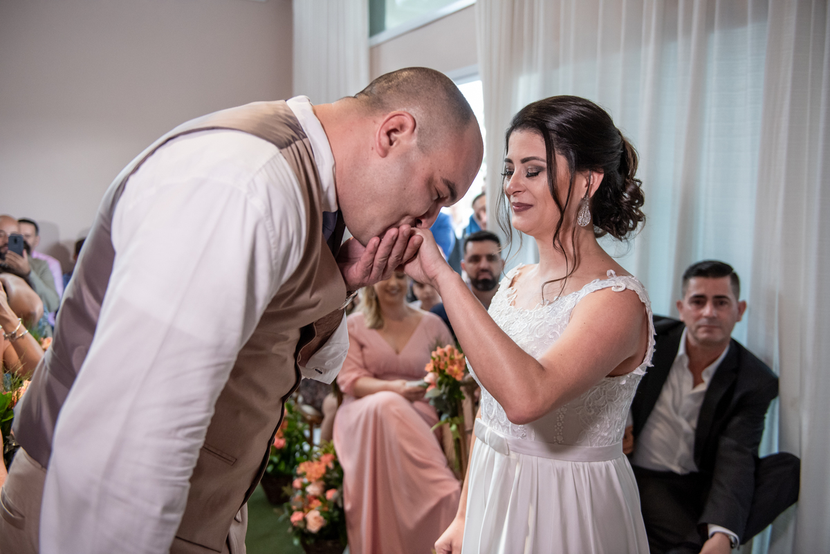 Noivo beija a mão da noiva em casamento civil.