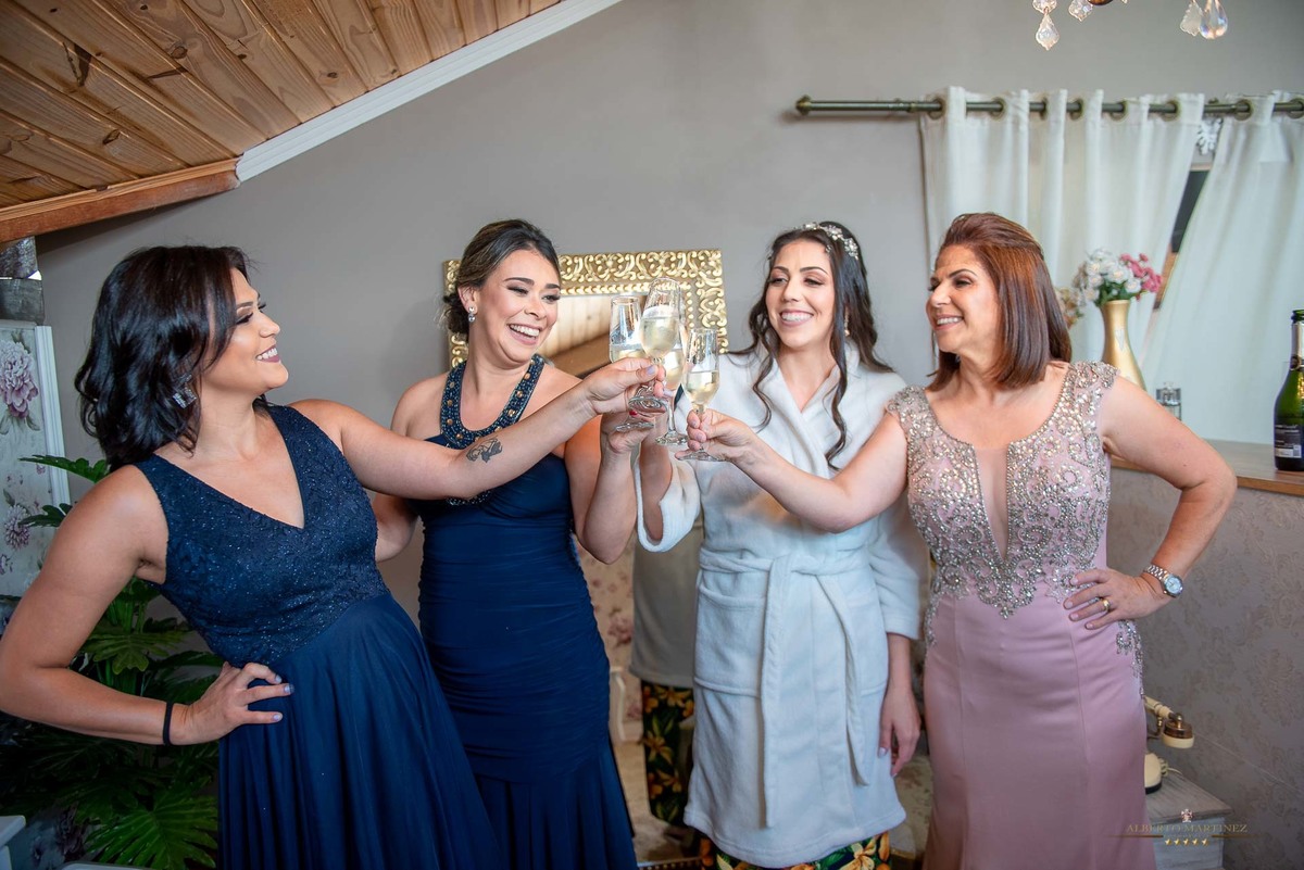 Noiva com a mãe e madrinhas fazendo um brinde