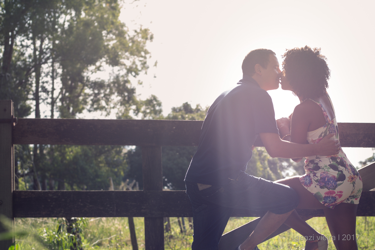 Foto de casal se beijando em porteira no campo 