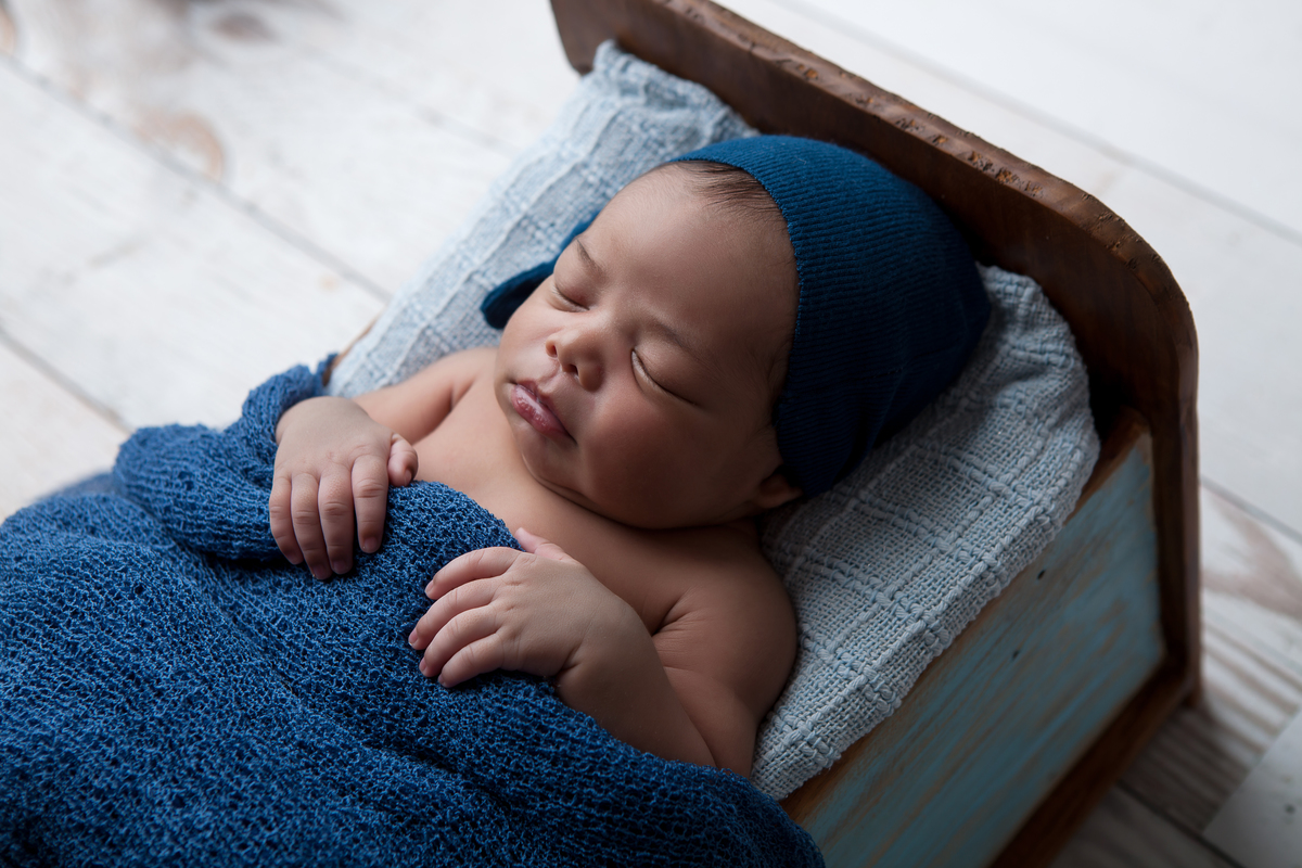 Fotografia de bebê newborn com touca azul, realizada no Estúdio Fotográfico Rosi Lima Fotografia, localizado na região do Barreiro, cidade de Belo Horizonte -  MG