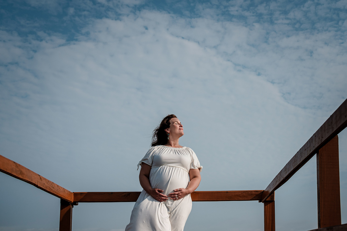 gestante com mãos na barriga dentro de uma pirâmide feita de nuvens no céu