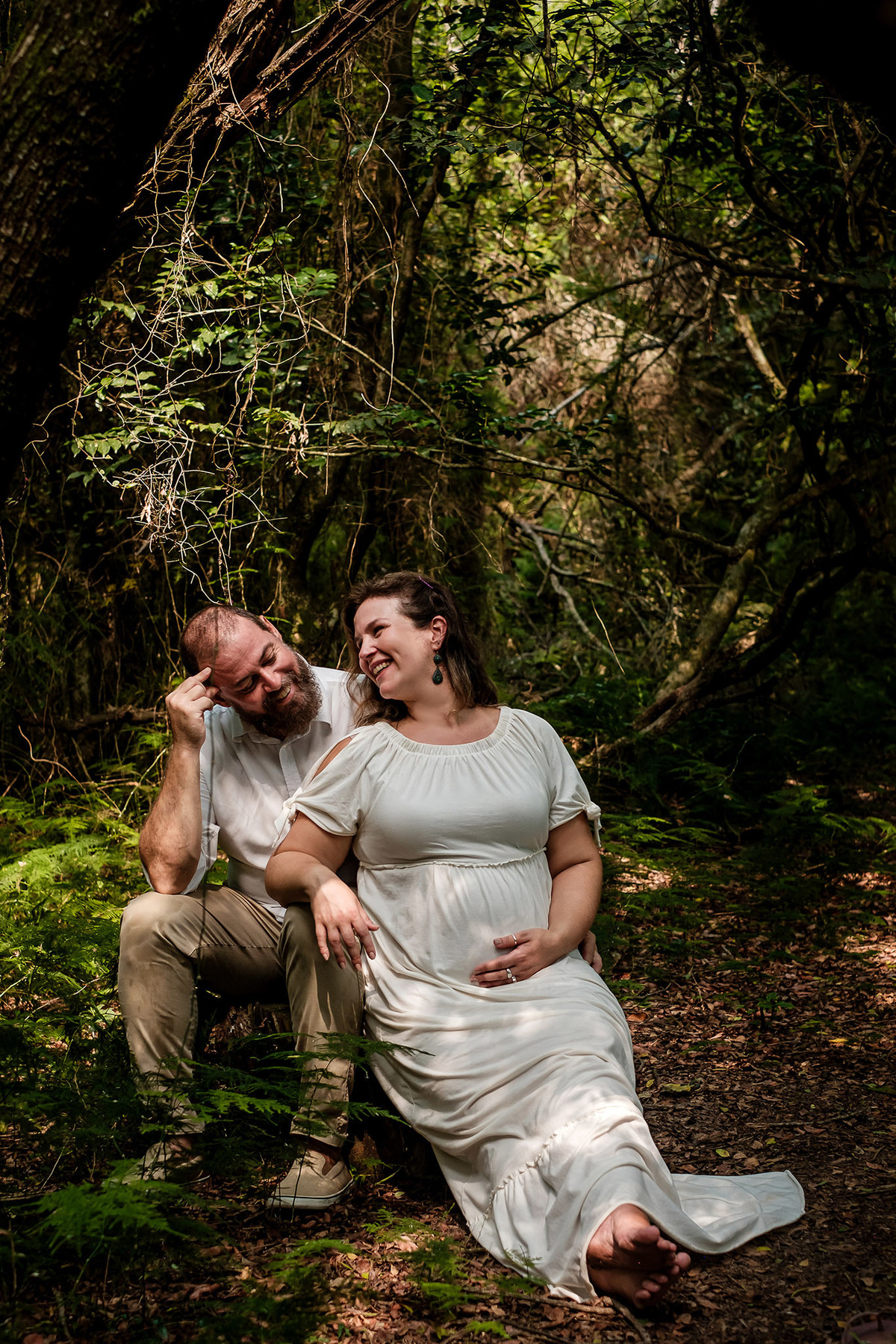 mulher gestante e homem sorrindo na floresta