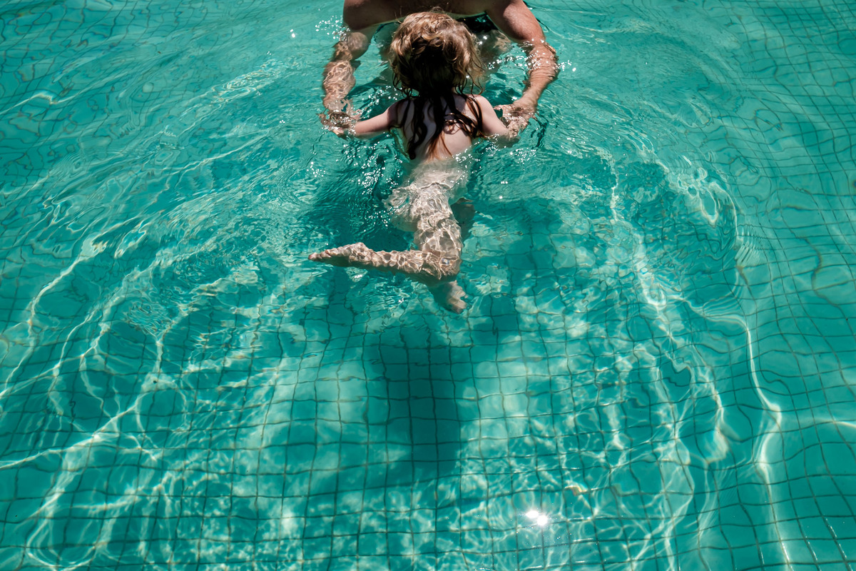 criança na piscina de mão com o pai