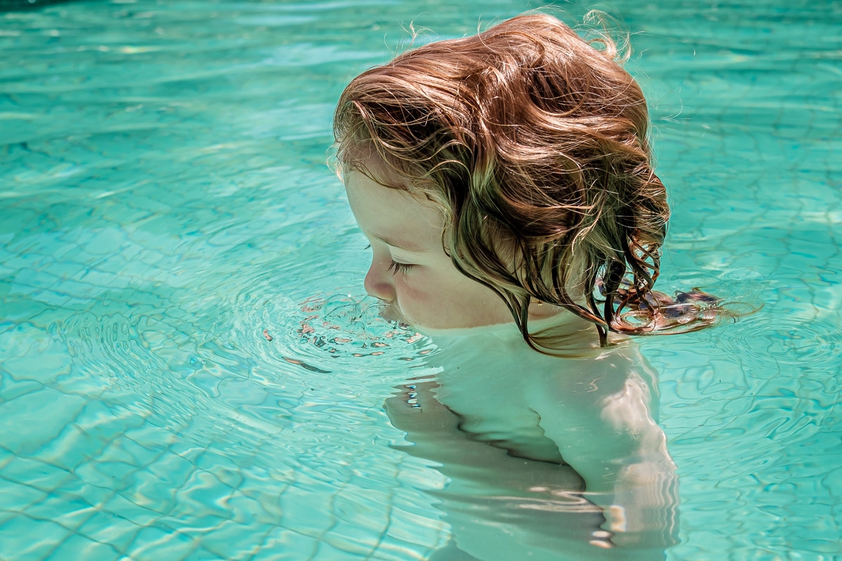 criança fazendo bolhas na água da piscina